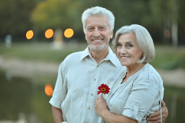 Divertida pareja de ancianos sonriente feliz con flor