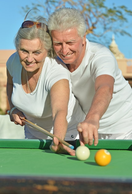 Divertida pareja de ancianos de vacaciones jugando al billar