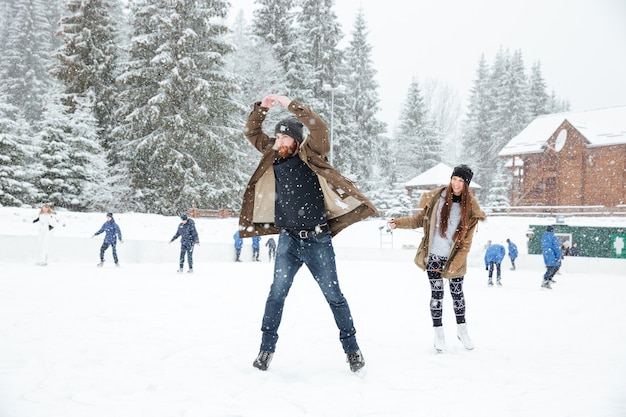 Divertida pareja joven patinaje sobre hielo al aire libre