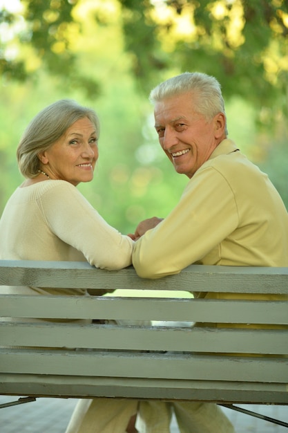 Divertida pareja senior sentada en un banco en el parque
