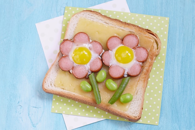 Divertidas tostadas con queso y flor de salchichas, judías verdes y huevos de codorniz