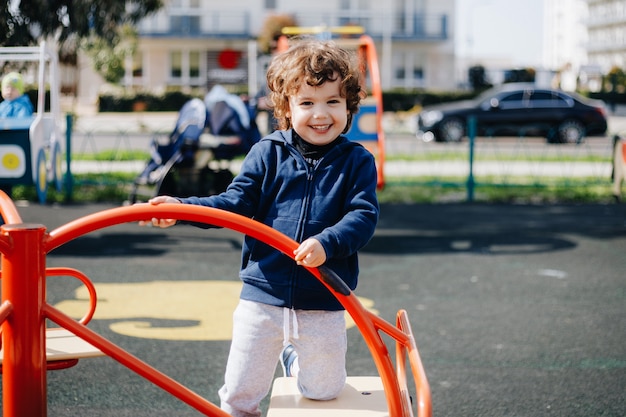 Divertido lindo bebé feliz jugando en el patio de recreo. La emoción de la felicidad, la diversión, la alegría. Sonrisa de un niño.