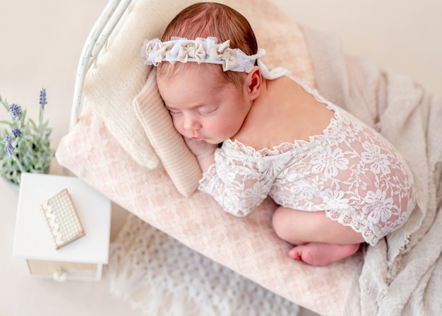 Divertido recién nacido durmiendo en cama pequeña