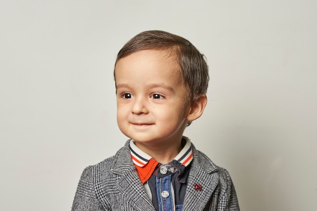 Divertido retrato de un niño de 2 años con un elegante traje hecho a mano.