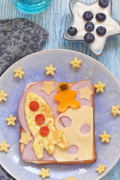 Divertido sándwich con cohete y cosmonauta en la luna de queso