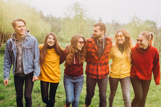 Divertido selfie con amigos. Compañía de amigos alegres haciendo selfie y sonriendo mientras está de pie al aire libre. la gente usa puentes rojos y amarillos. jóvenes descansando en la naturaleza, hablando y riendo