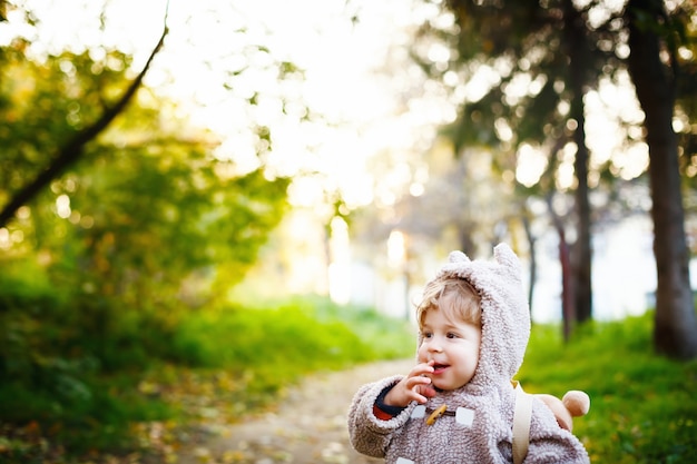 Divertido tímido pequeño niño de 2 años riéndose en el parque al atardecer. Concepto de infancia feliz. Espacio para su texto.