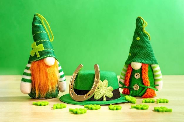 Divertidos gnomos irlandeses hojas de trébol decorativas y herradura para la buena suerte en la mesa de madera Feliz día de San Patricio