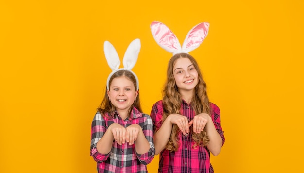 Divertidos niños positivos de pascua en orejas de conejo sobre fondo amarillo