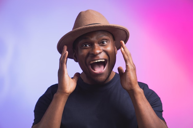 Divertimento animado masculino afro-americano exclama em felicidade espera receber gestos de surpresa agradáveis expressa ativamente grande surpresa no fundo rosa