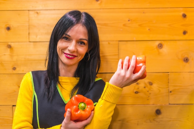 Divertindo-se com pimentas vermelhas na mão de uma menina de frutas caucasiana morena