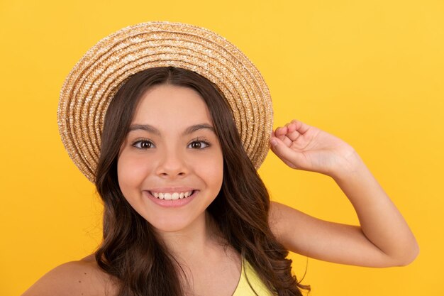 Divertindo-se no tempo de selfie, a criança usa chapéu de palha sorrindo adolescente com cabelo encaracolado em fundo amarelo