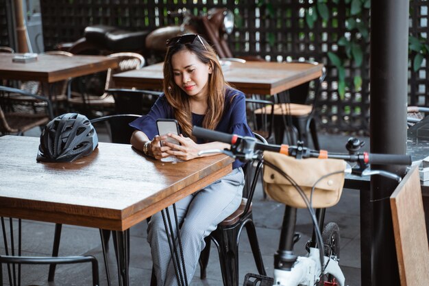 Divertir-se mulher asiática usando smartphone quando uma pausa no café