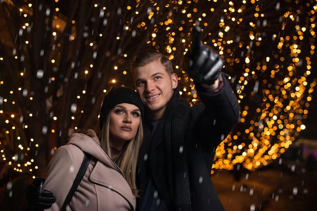 Divertirse juntos en un hada de Navidad Joven pareja alegre está dando un paseo disfrutando vestidos cálidos mirándose y riendo