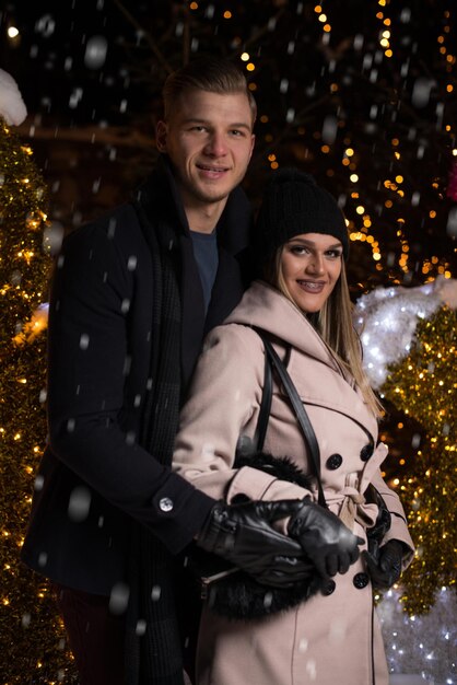 Divertirse juntos en un hada de Navidad Joven pareja alegre está dando un paseo disfrutando vestidos cálidos mirándose y riendo