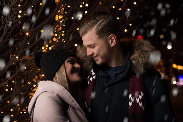 Divertirse juntos en un hada de Navidad Joven pareja alegre está dando un paseo disfrutando vestidos cálidos mirándose y riendo