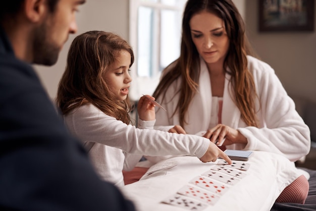 Divertirse con mamá y papá Foto de una familia joven jugando a las cartas juntos en casa