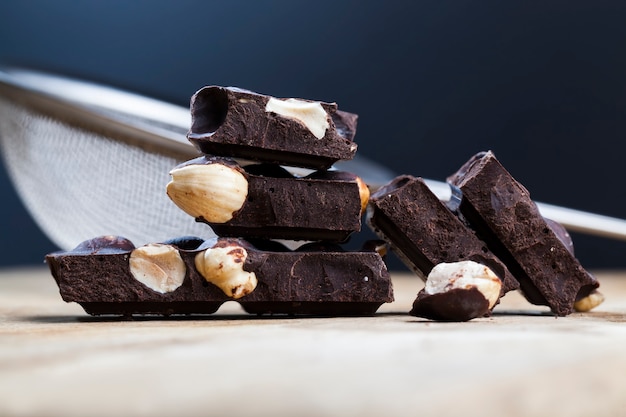 Dividida en partes barra de chocolate con nueces enteras, chocolate dulce con nueces troceadas, trozos de chocolate con avellanas con cacao y azúcar