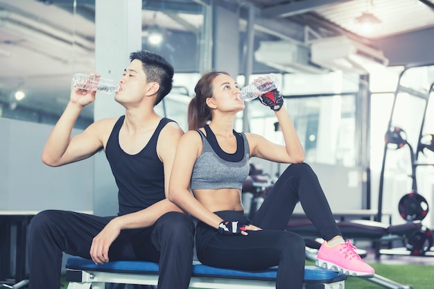 Diviértase el agua potable del hombre y de la mujer en gimnasio o club de deporte después de entrenamiento.