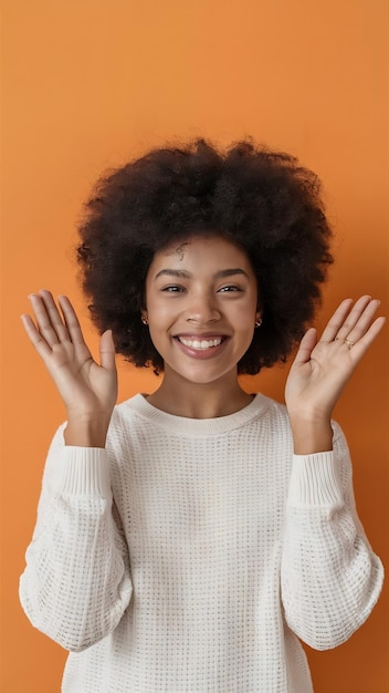 Se divierte una chica bonita con el pelo afro rizado levanta las palmas tiene una expresión alegre sonríe ampliamente ver