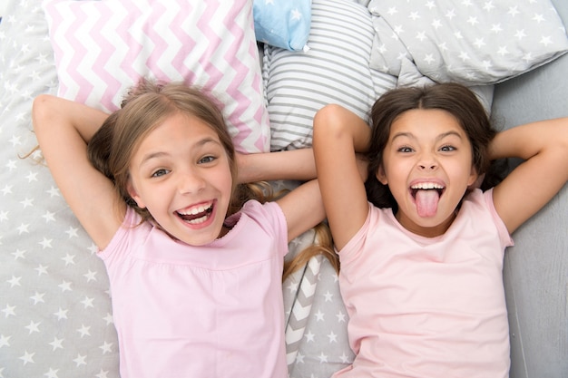 Divirtiéndose con el mejor amigo. Los niños de humor alegre y juguetón se divierten juntos. Fiesta de pijamas y amistad. Hermanas niños pequeños felices relajándose en el dormitorio. Amistad de niñas pequeñas. Ocio y diversión.