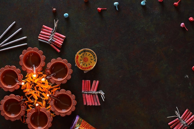 Diwali Diya mit Feuerwerkskörpern und Blumendekoration Rangoli, Diwali-Lampe von Hand beleuchtet, Draufsicht