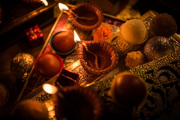 Diwali diya o iluminación en la noche con regalos, flores sobre una escena cambiante
