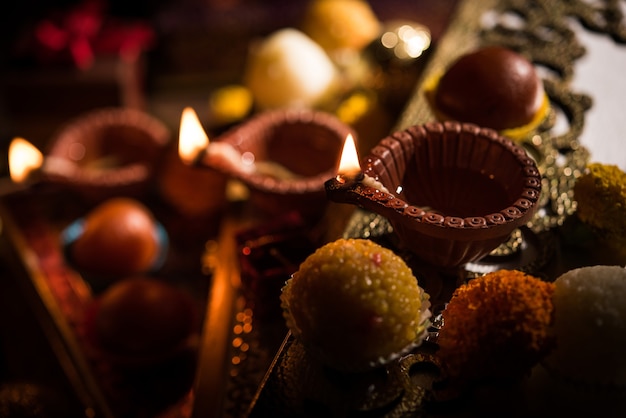 Diwali diya ou iluminação à noite com presentes, flores em um cenário sombrio