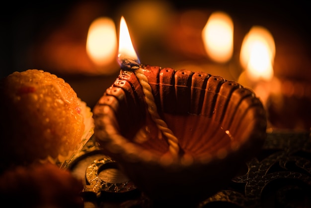 Diwali diya ou iluminação à noite com presentes, flores em um cenário sombrio