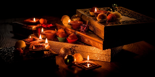 Diwali diya ou iluminação à noite com presentes, flores em um cenário sombrio