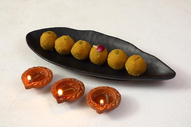 Diwali Rangoli usando Diya y besan laddu, Laddoo sobre fondo blanco, festival hindú de luces