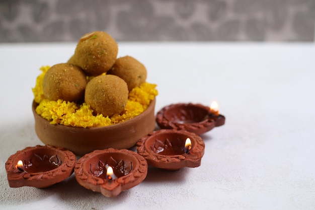 Diwali Rangoli usando Diya, flores e Besan Laddu sobre fundo branco, foco seletivo