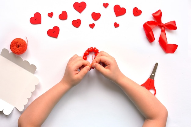 DIY bolígrafos bebé pulsera anudada de corazones de cuentas rojas para el día de san valentín. decoración de bebé hecha a mano. concepto de artesanía.