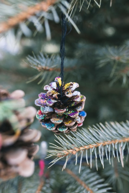 DIY handgefertigte bemalte Tannenzapfendekoration auf einem Weihnachtsbaum