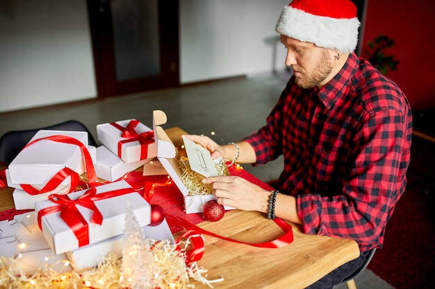 DIY Man in Santa hat haciendo tarjetas de felicitación para Año Nuevo y Navidad para amigos o familiares