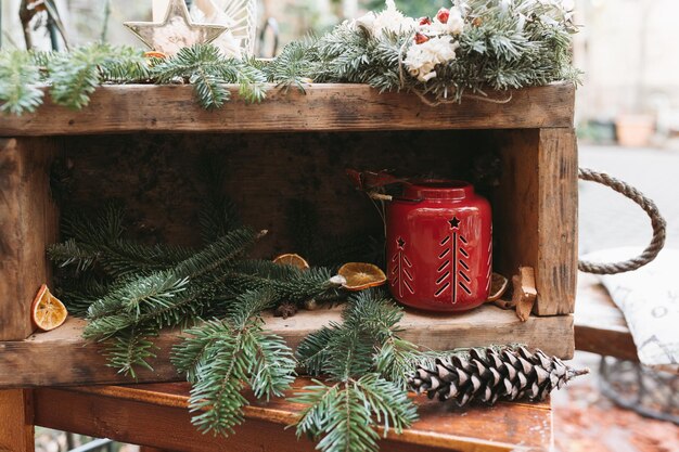 DIY natürliche Weihnachtsdekoration und rote Kerzenlaterne im Freien Tannenzweig mit Tannenzapfen in Schachtel