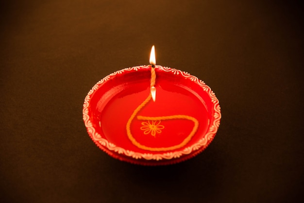 Diya de arcilla decorativa roja grande o lámpara de aceite encendida durante el festival de diwali. Enfoque selectivo