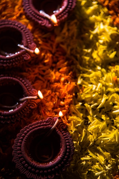 Diya tradicional ou lamparina a óleo acesa em rangoli coloridos feitos de pétalas de flores, no festival de luzes chamado diwali ou deepawali, foco seletivo