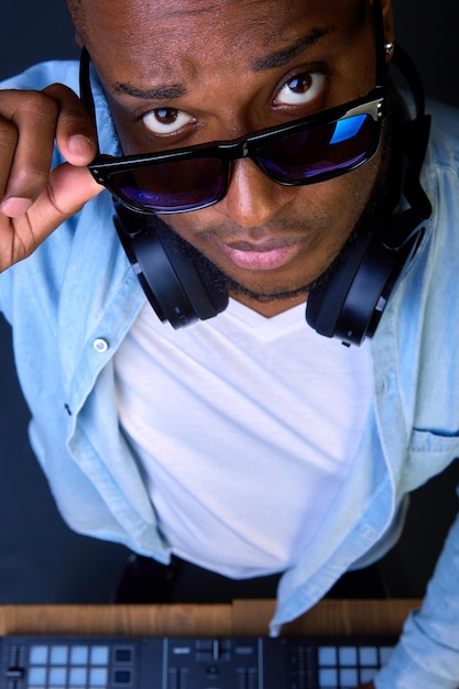 Dj afroamericano con gafas oscuras mira a la cámara