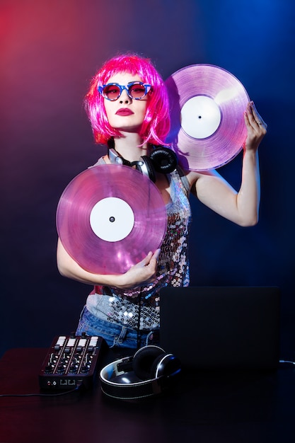 Dj con auriculares, cabello rosa y discos de vinilo rosa