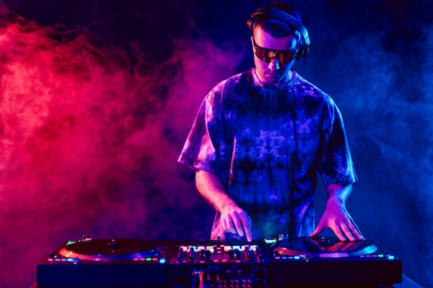 DJ de club tocando música en una fiesta con gafas de sol