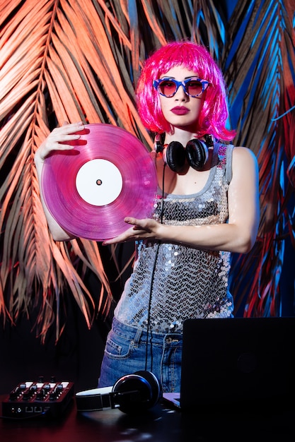 Dj com fones de ouvido, cabelo rosa e discos de vinil rosa