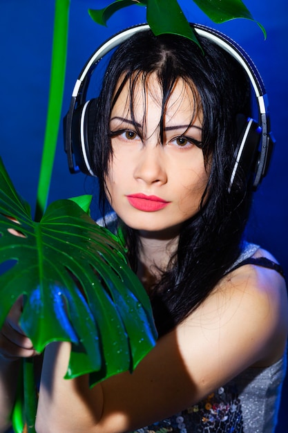 Dj com fones de ouvido com folhas tropicais verdes de monstera