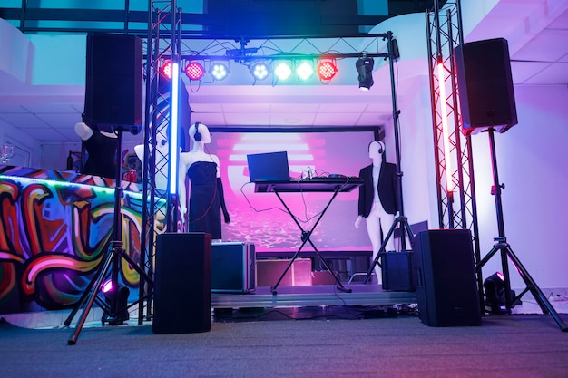 DJ-Controller auf der Bühne einer Diskothek in einem leeren Nachtclub ohne Leute. Elektronische Musikerkonsolenausrüstung, Lautsprecher und Scheinwerfer für Live-Musikkonzert im dunklen Club.