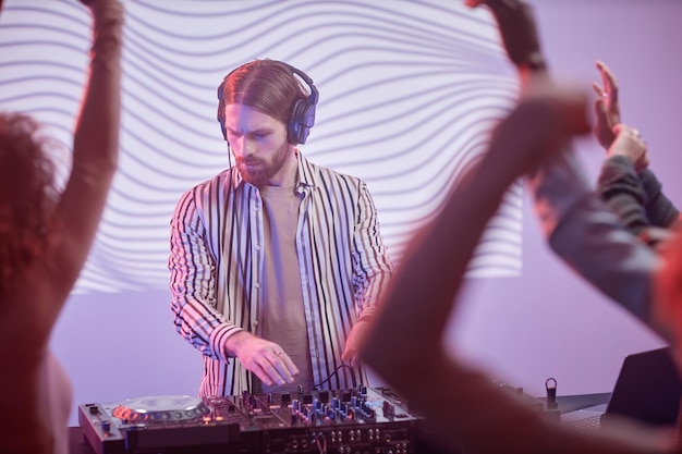 Dj de cabelos compridos por plataforma giratória em luzes de neon
