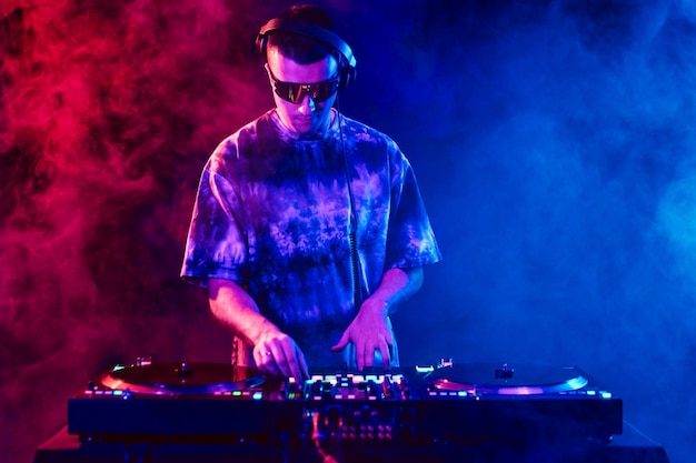 DJ de clube tocando música em uma festa usando óculos de sol