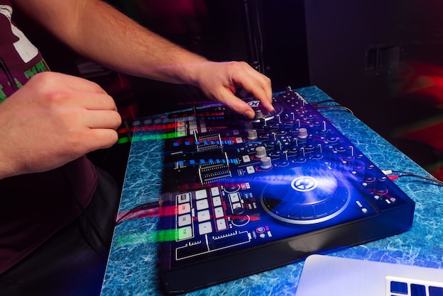 Dj de mãos tocando e mixando música no controlador de música em uma festa