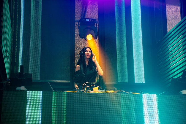 DJ en el escenario en discoteca club nocturno mezclando ritmo de música techno