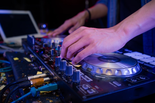 DJ en el escenario de mezclas, disc jockey y pistas en el controlador de mezclador de sonido, tocando música en la fiesta del club nocturno.