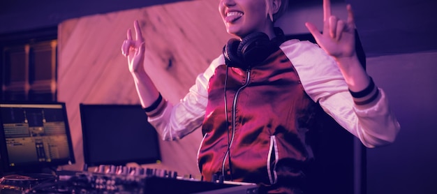 Dj femenina divirtiéndose mientras reproduce música en el bar